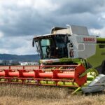 A powerful harvester working in a wheat field against a cloudy sky, demonstrating modern agriculture.