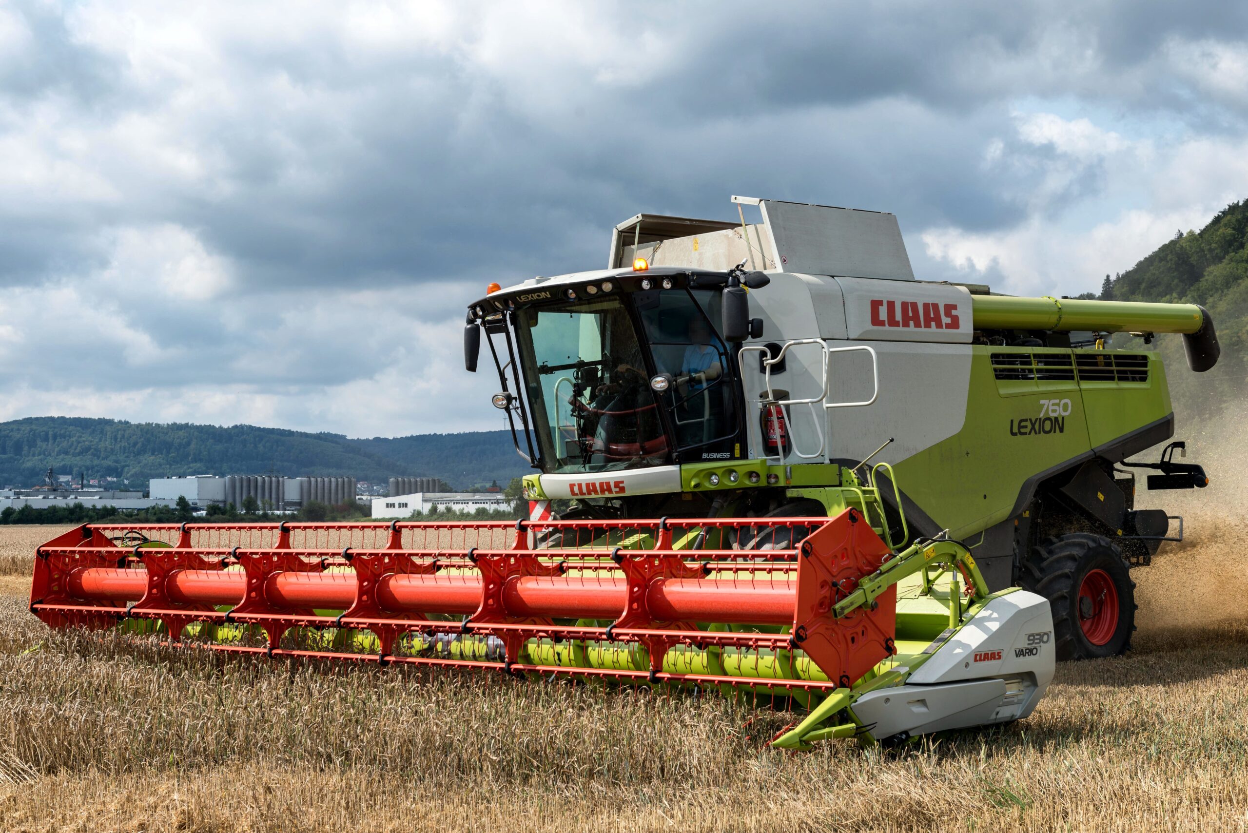 A powerful harvester working in a wheat field against a cloudy sky, demonstrating modern agriculture.